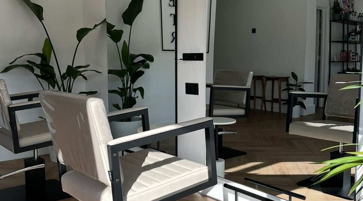 Elegant interior of Luke East Hair in Birmingham, England, GB, featuring modern chairs and lush plants.