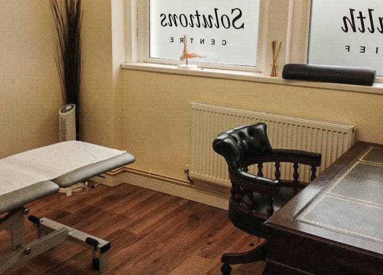 Cozy therapy room at Swansea Health Solutions, Gowerton, Wales, GB featuring massage bed and elegant chair.