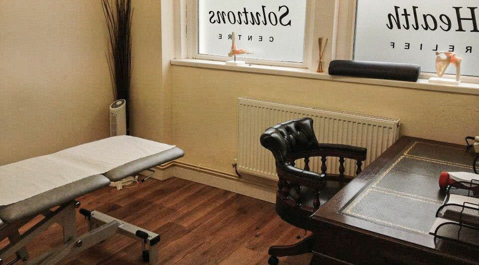 Cozy therapy room at Swansea Health Solutions, Gowerton, Wales, GB featuring massage bed and elegant chair.