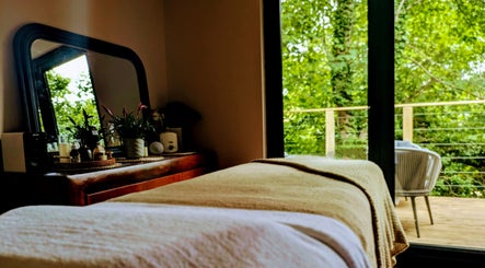 Serene massage room at Sakura Wellness Institute, Audley, England, GB with a tranquil forest view.