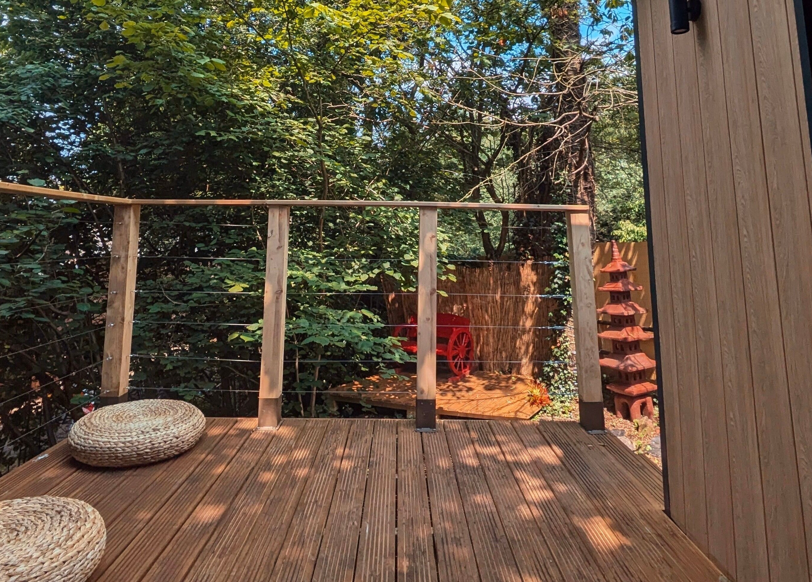 Relax on the serene wooden terrace of Sakura Wellness Institute in Audley, England, surrounded by lush greenery.