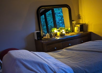 Massage room at Sakura Wellness Institute, Audley, England, GB, featuring a cozy bed and ambient lighting.