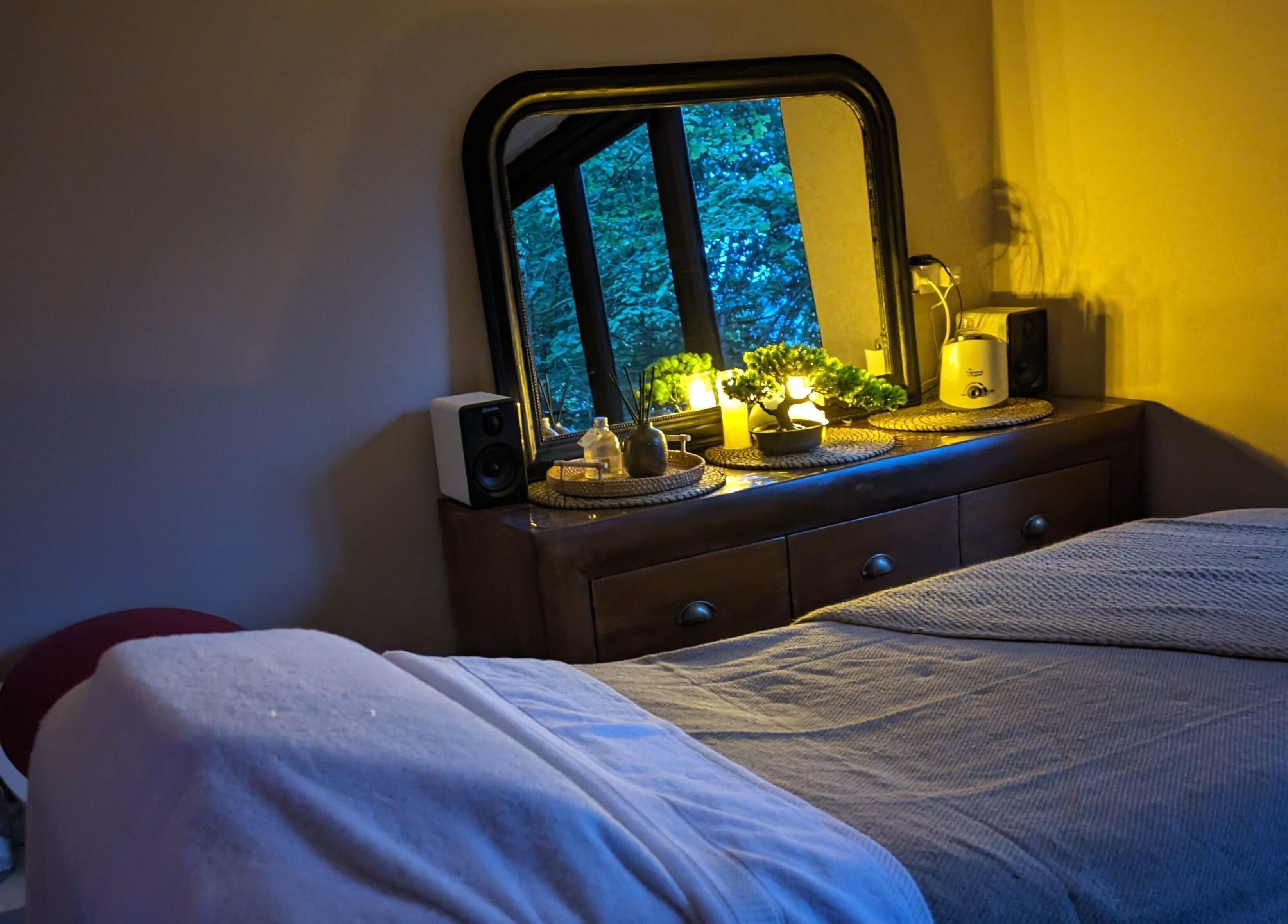 Massage room at Sakura Wellness Institute, Audley, England, GB, featuring a cozy bed and ambient lighting.