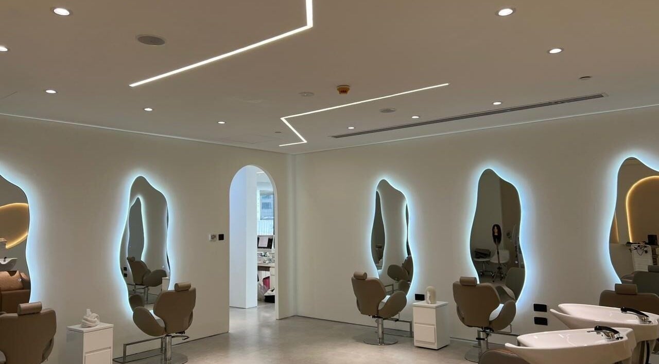 Interior of Hadil Strokes Beauty Salon in Dubai, Dubai, AE, featuring stylish chairs and illuminated mirrors.