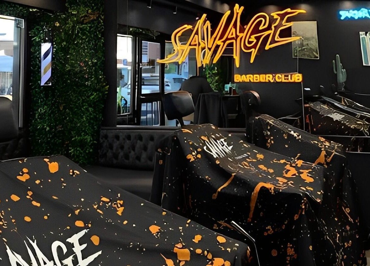Interior de Savage Barber Club en Buenos Aires, con modernos sillones y neón decorativo.