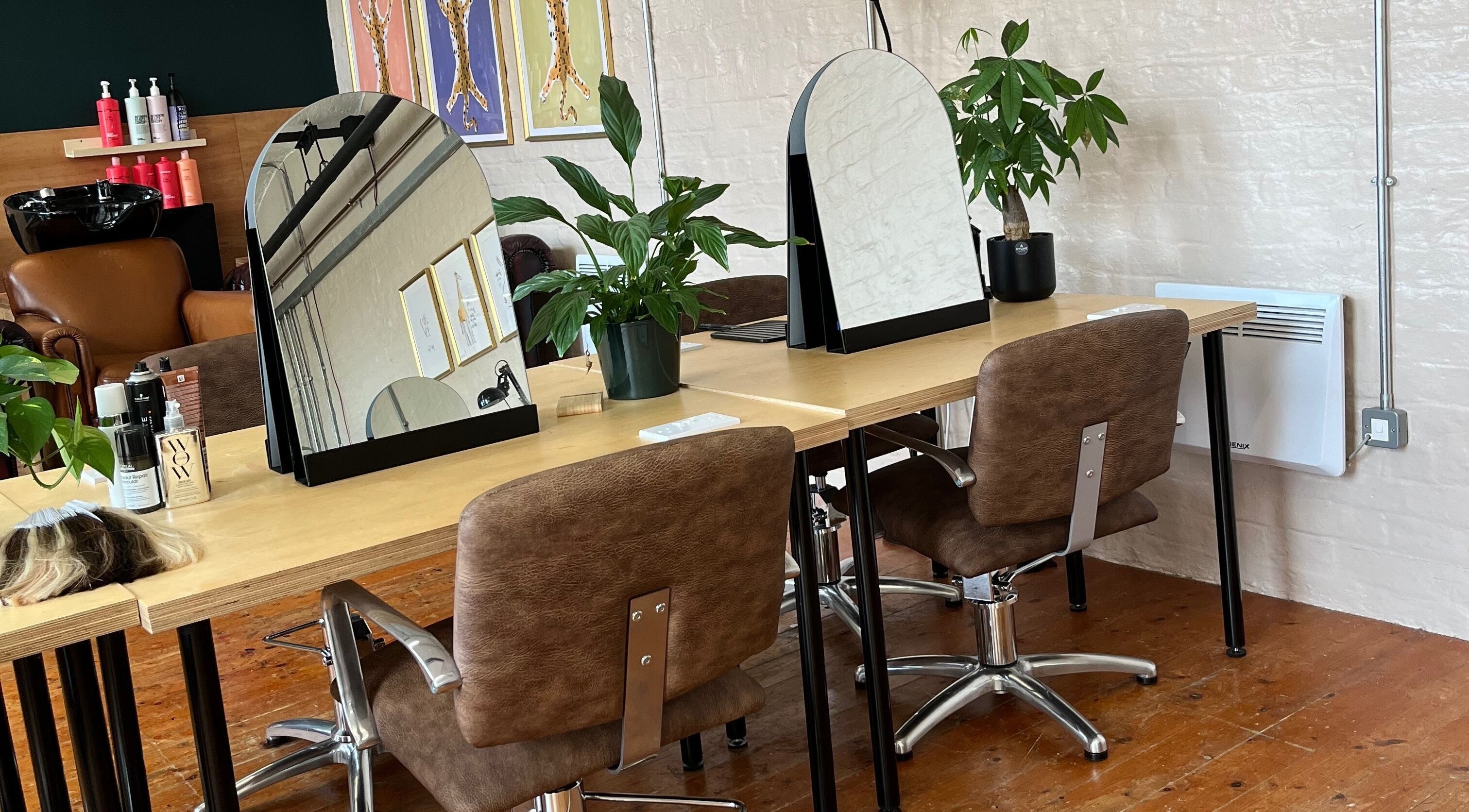 Modern salon interior at Laura Does Hair in Leeds, England, GB, featuring mirrors and brown leather chairs.