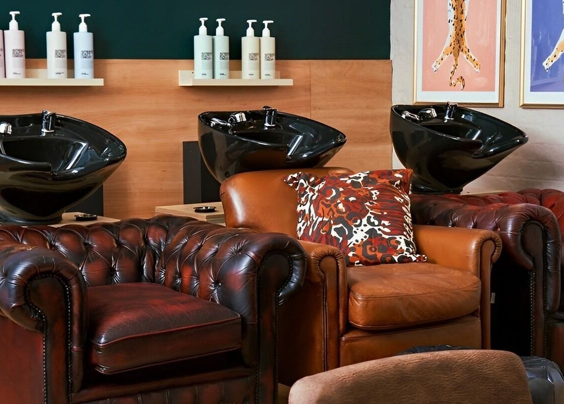 Chic washing area at Laura Does Hair in Leeds, England, GB featuring plush leather chairs and sleek basins.