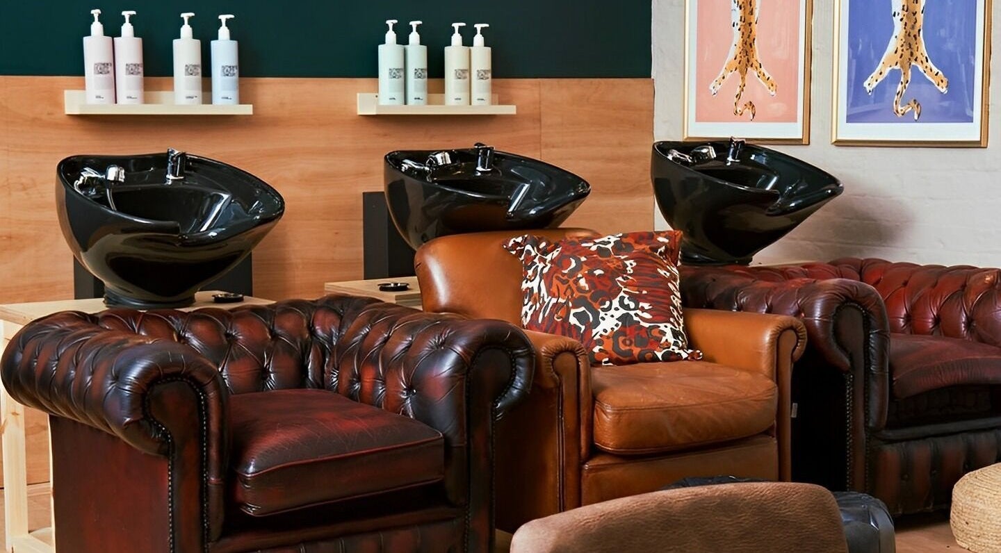 Chic washing area at Laura Does Hair in Leeds, England, GB featuring plush leather chairs and sleek basins.