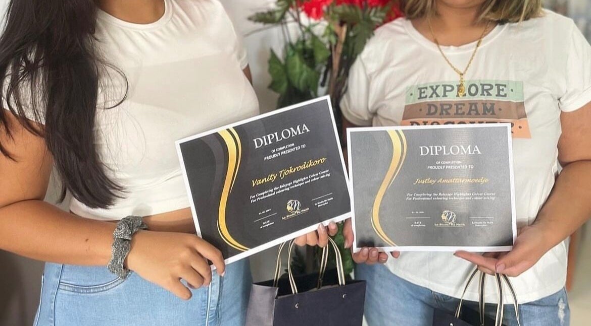 Graduates holding diplomas at Le Studio De Malik, Paramaribo, Paramaribo, SR. Celebrating achievements.