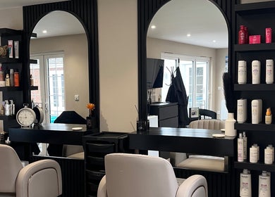 Elegant interior of 'Hair by Tia' salon in Stanway, England, GB, featuring modern decor and styling stations.
