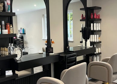 Hair by Tia's elegant salon interior in Stanway, England, GB, featuring stylish mirrors and salon chairs.