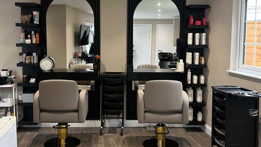 Elegant salon workspace at Hair by Tia, Stanway, England, GB with modern chairs and shelves of beauty products.