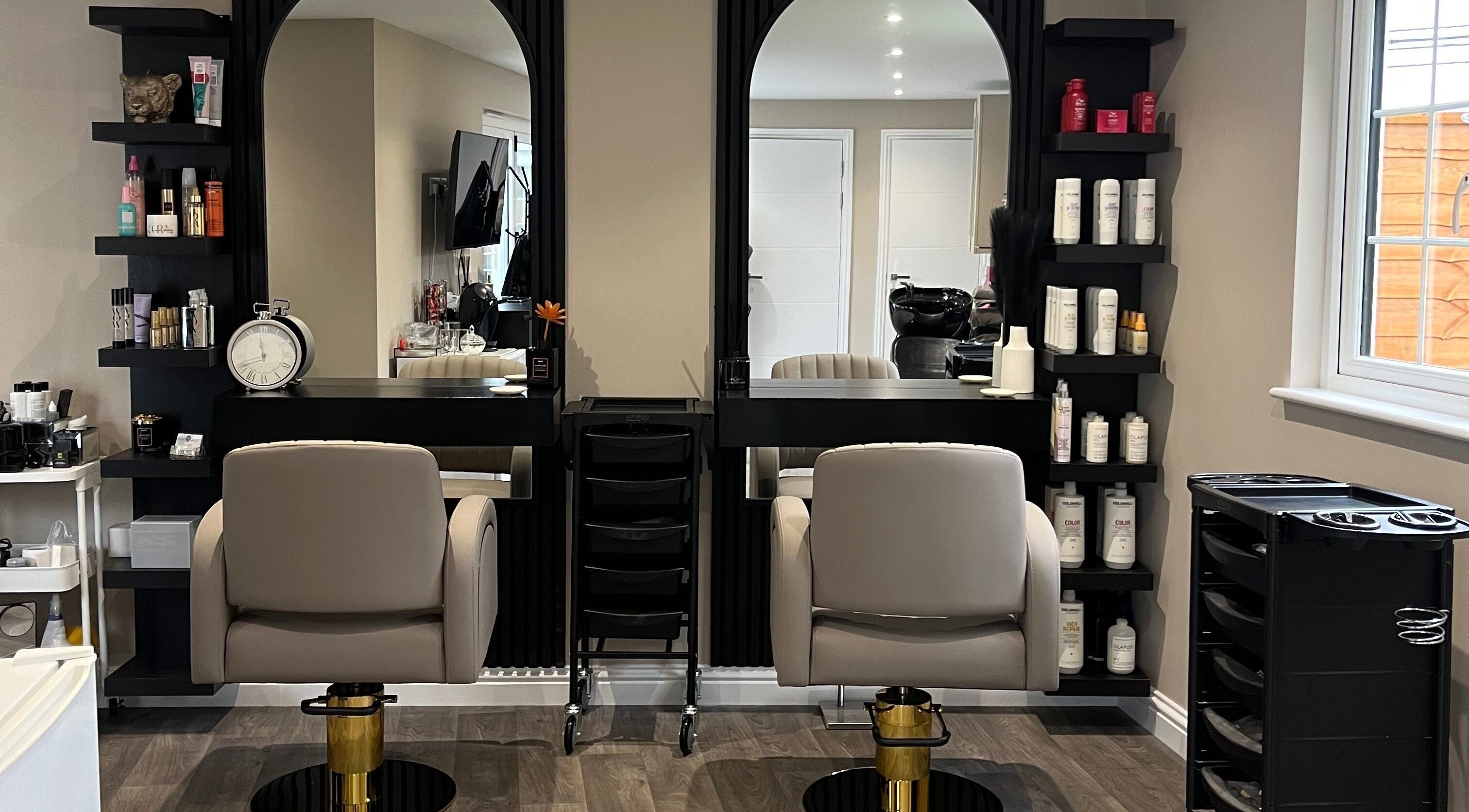 Elegant salon workspace at Hair by Tia, Stanway, England, GB with modern chairs and shelves of beauty products.