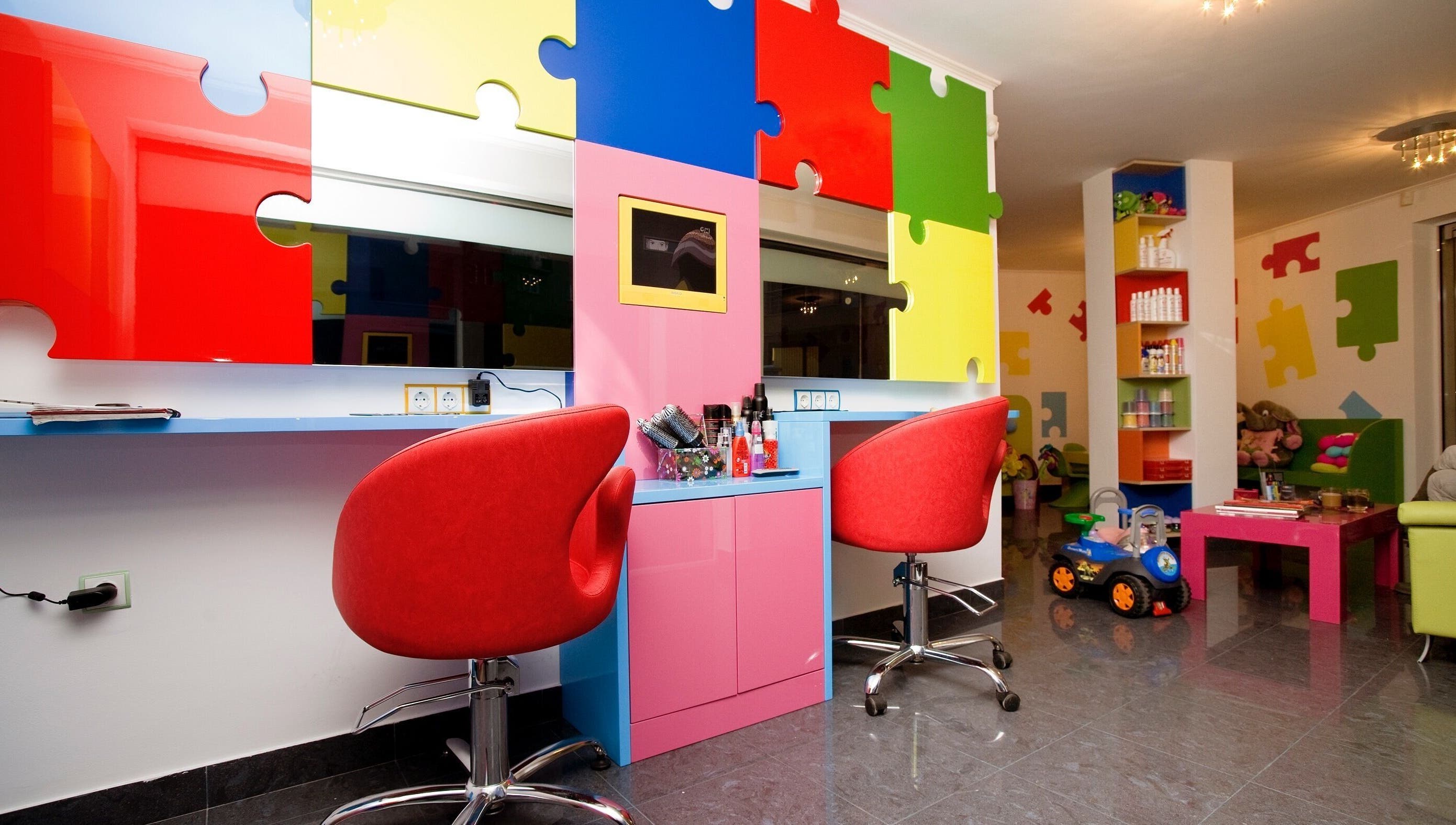 Ярко оцветена стая в ПЪЗЕЛ София кв. Дружба, София, BG с пъзел стени и червени столове.