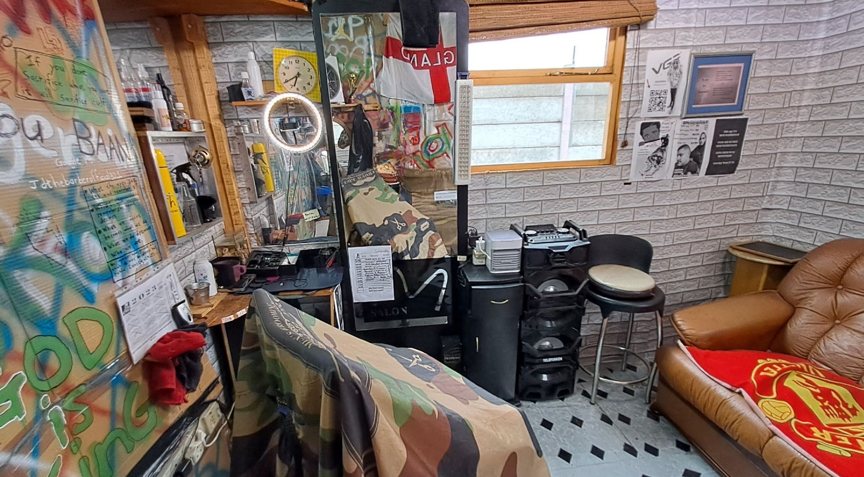 Eclectic barbershop interior at Jd Cuts, Cape Town, Western Cape, ZA, featuring a graffiti-styled wall and cozy seating.