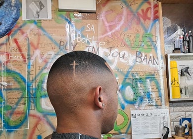 Stylish haircut with cross design at Jd Cuts, graffiti wall in Cape Town, Western Cape, ZA.