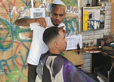 Stylist at Jd Cuts in Cape Town, Western Cape, ZA creating a precise hairstyle in a lively, colorful setting.
