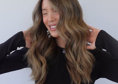 Smiling woman with wavy hair styled at Estrella Salon, San Diego, California, US.