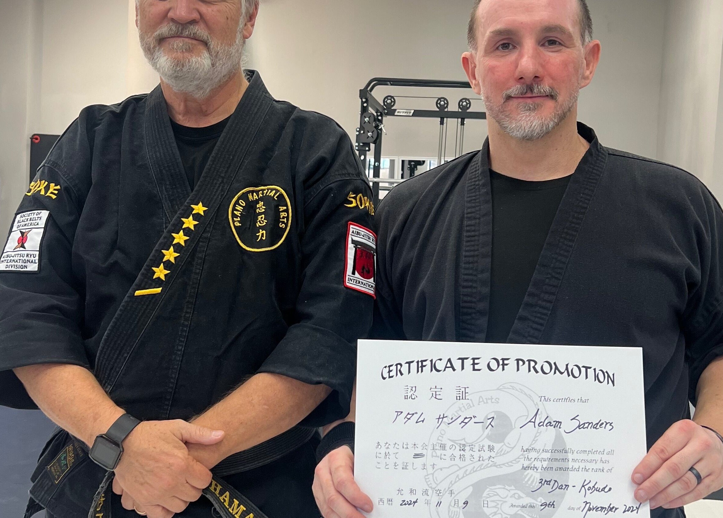 Two martial artists at Warrior’s Edge in Dallas, Texas, US, one holding a promotion certificate.