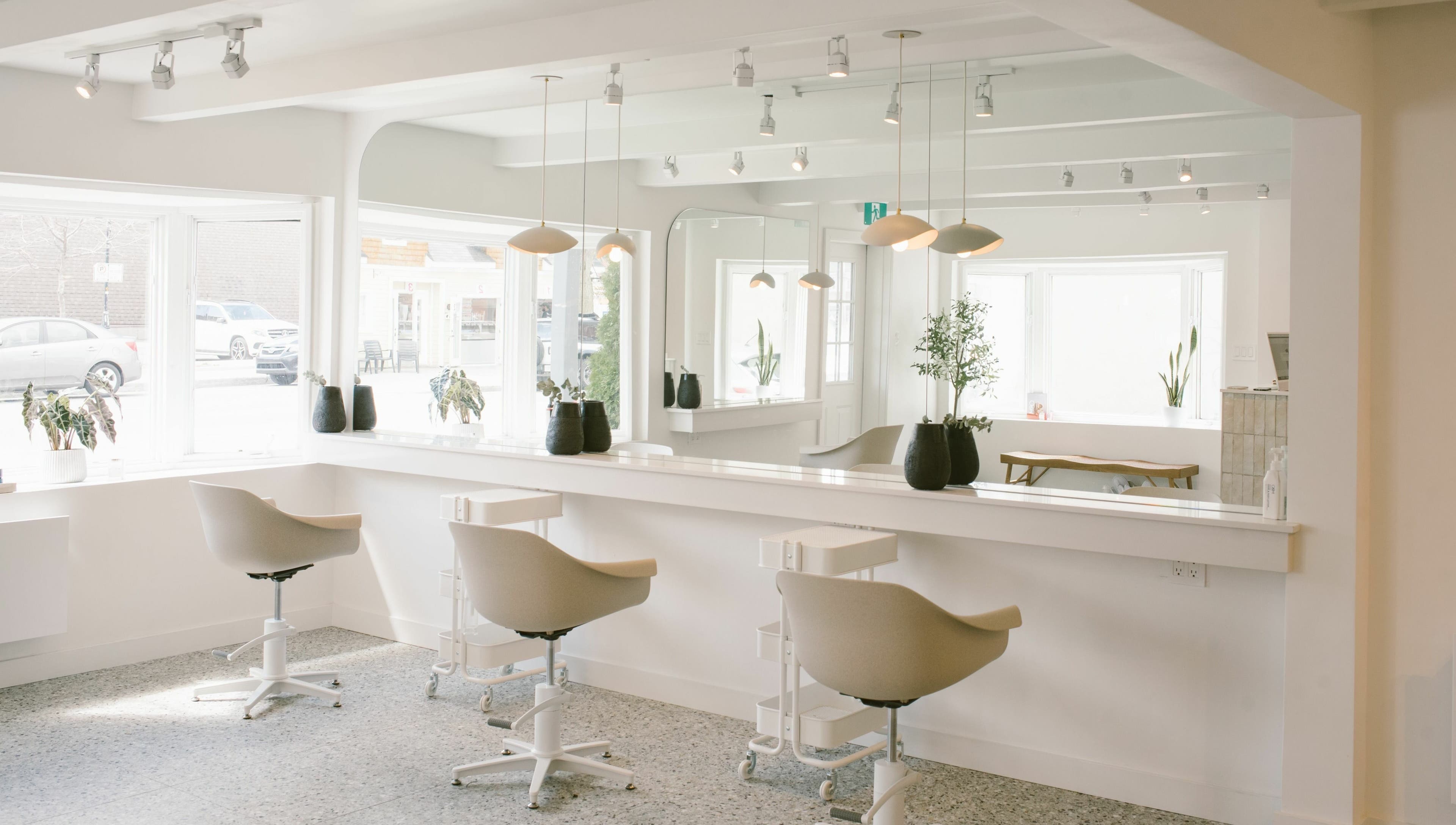 Intérieur moderne et lumineux de Mane by TK à Pointe-Claire, Québec, CA, avec chaises blanches.