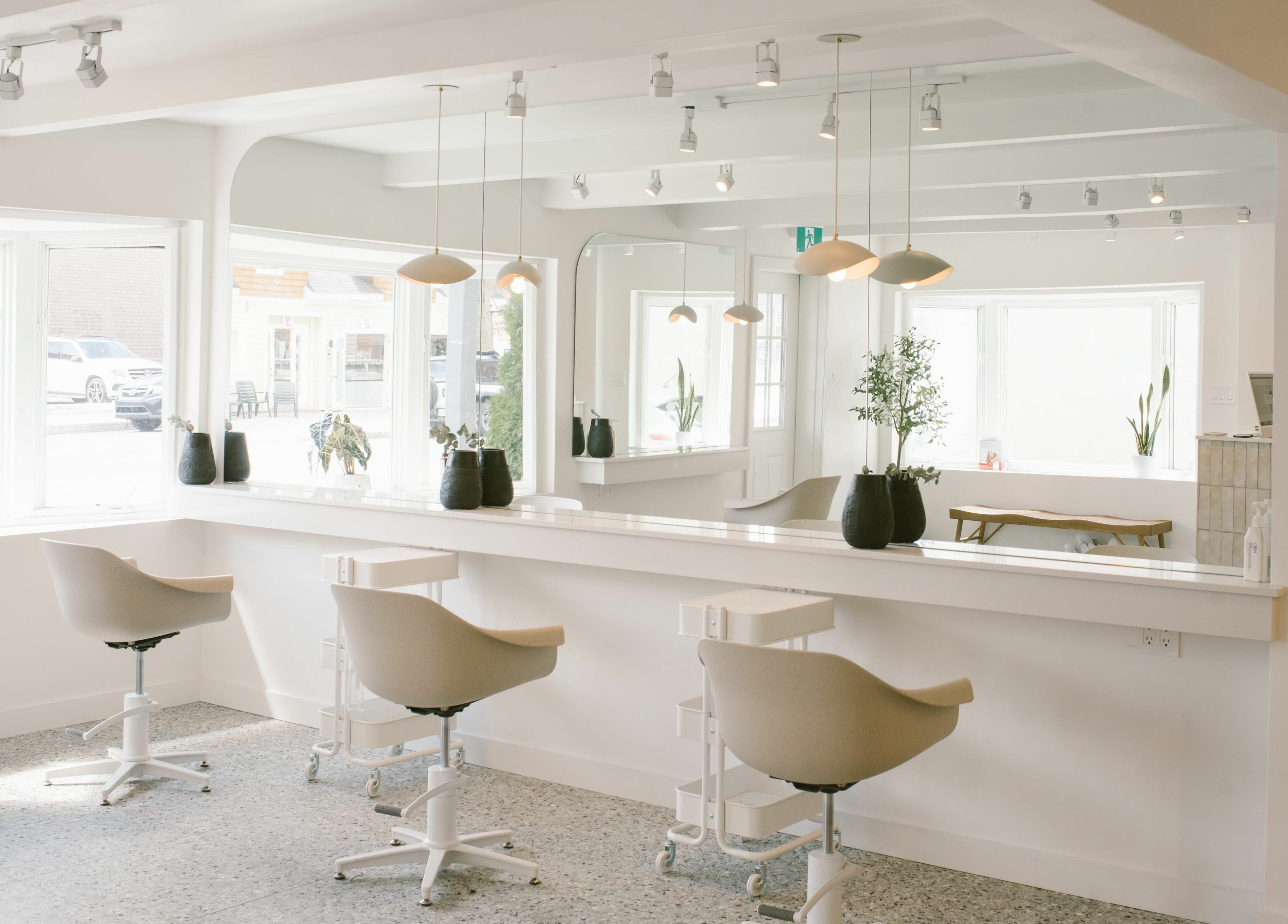 Intérieur moderne et lumineux de Mane by TK à Pointe-Claire, Québec, CA, avec chaises blanches.