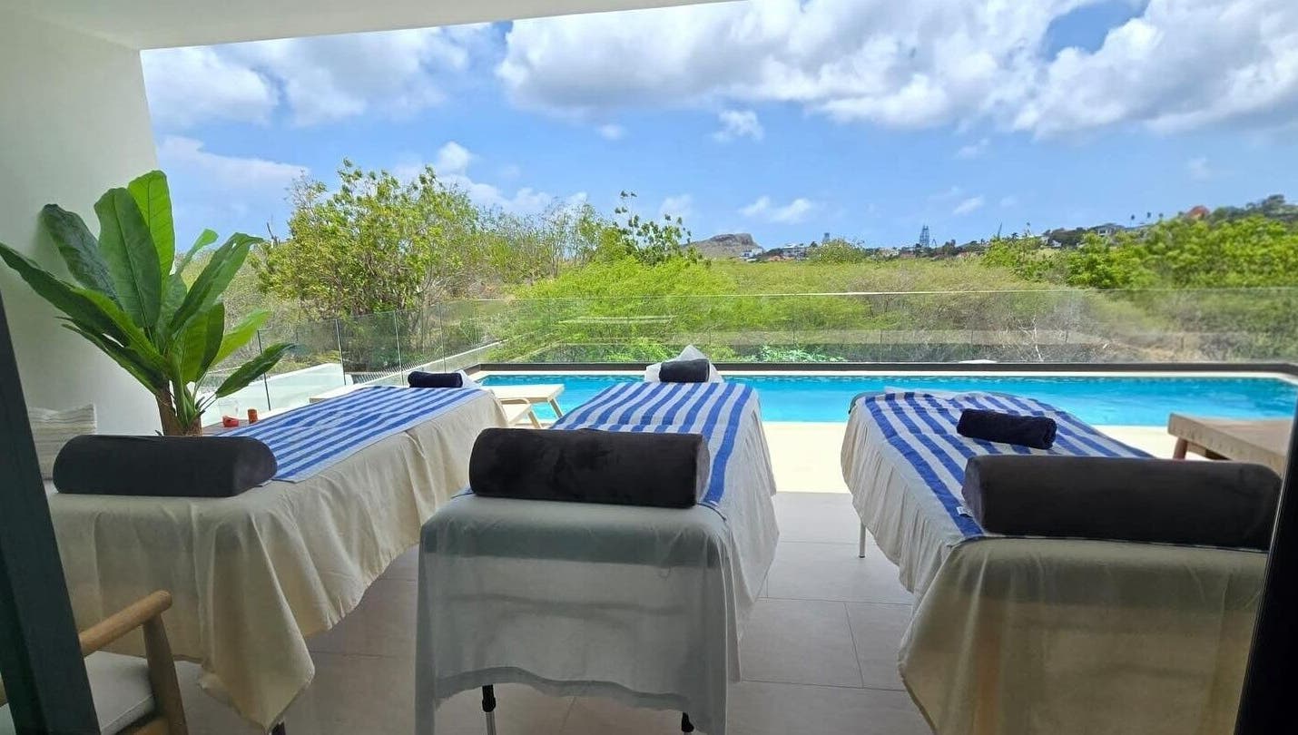 Tranquil massage tables by pool at I-Relax Massages, Willemstad, CW, offering a serene outdoor relaxation experience.