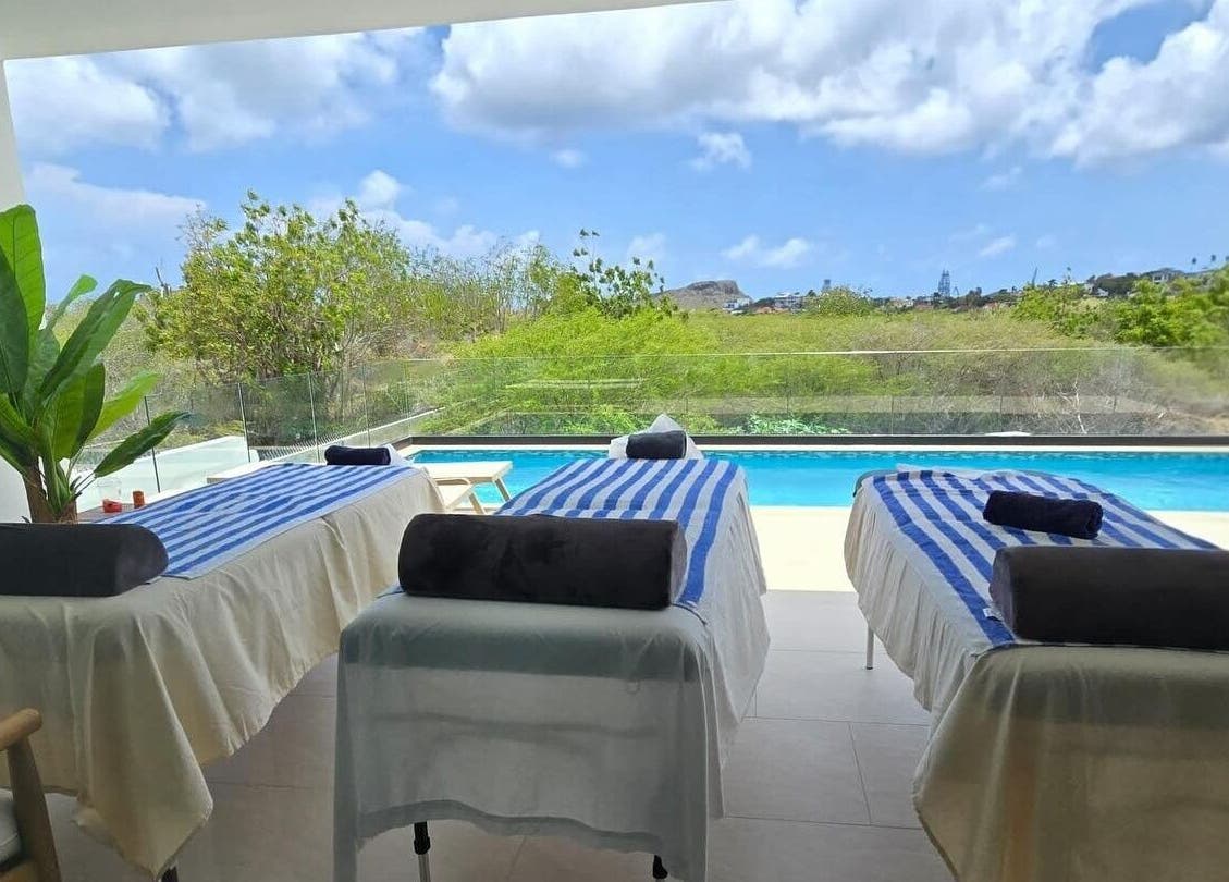 Tranquil massage tables by pool at I-Relax Massages, Willemstad, CW, offering a serene outdoor relaxation experience.