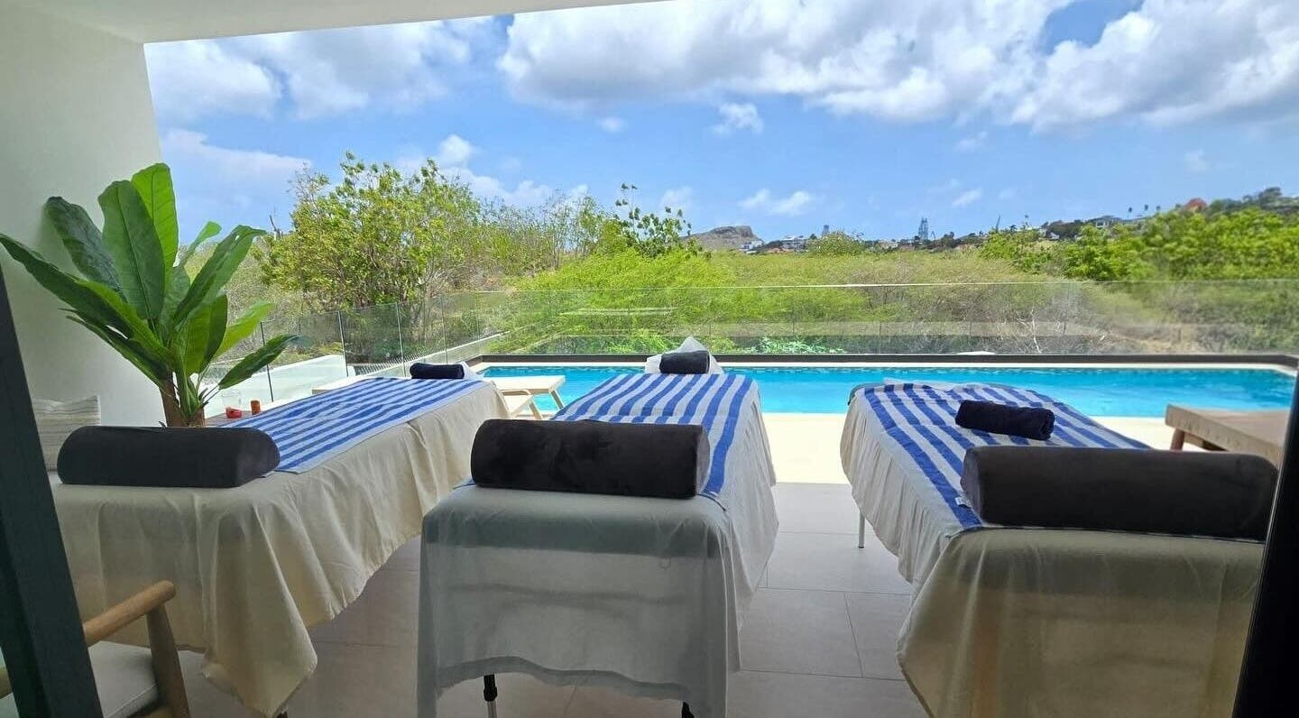 Tranquil massage tables by pool at I-Relax Massages, Willemstad, CW, offering a serene outdoor relaxation experience.