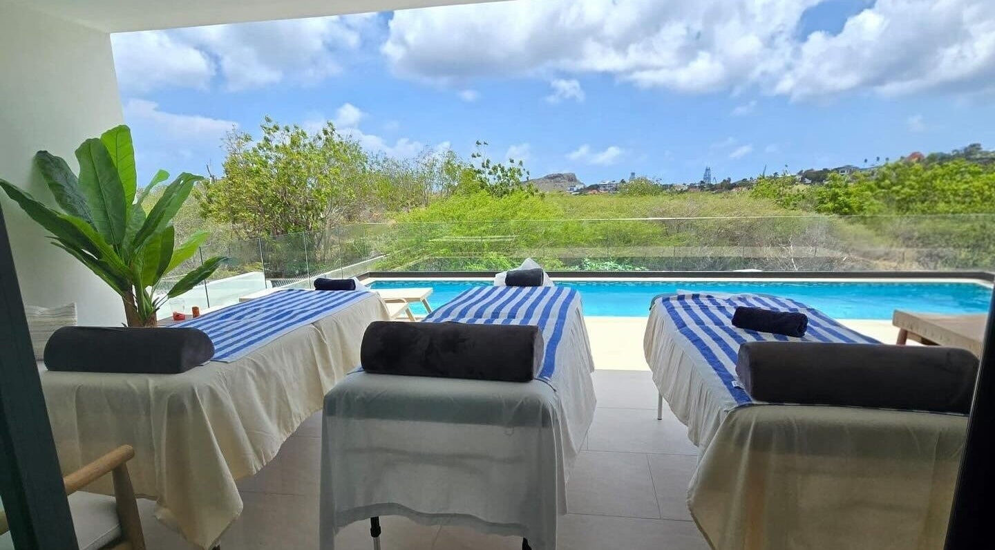 Tranquil massage tables by pool at I-Relax Massages, Willemstad, CW, offering a serene outdoor relaxation experience.