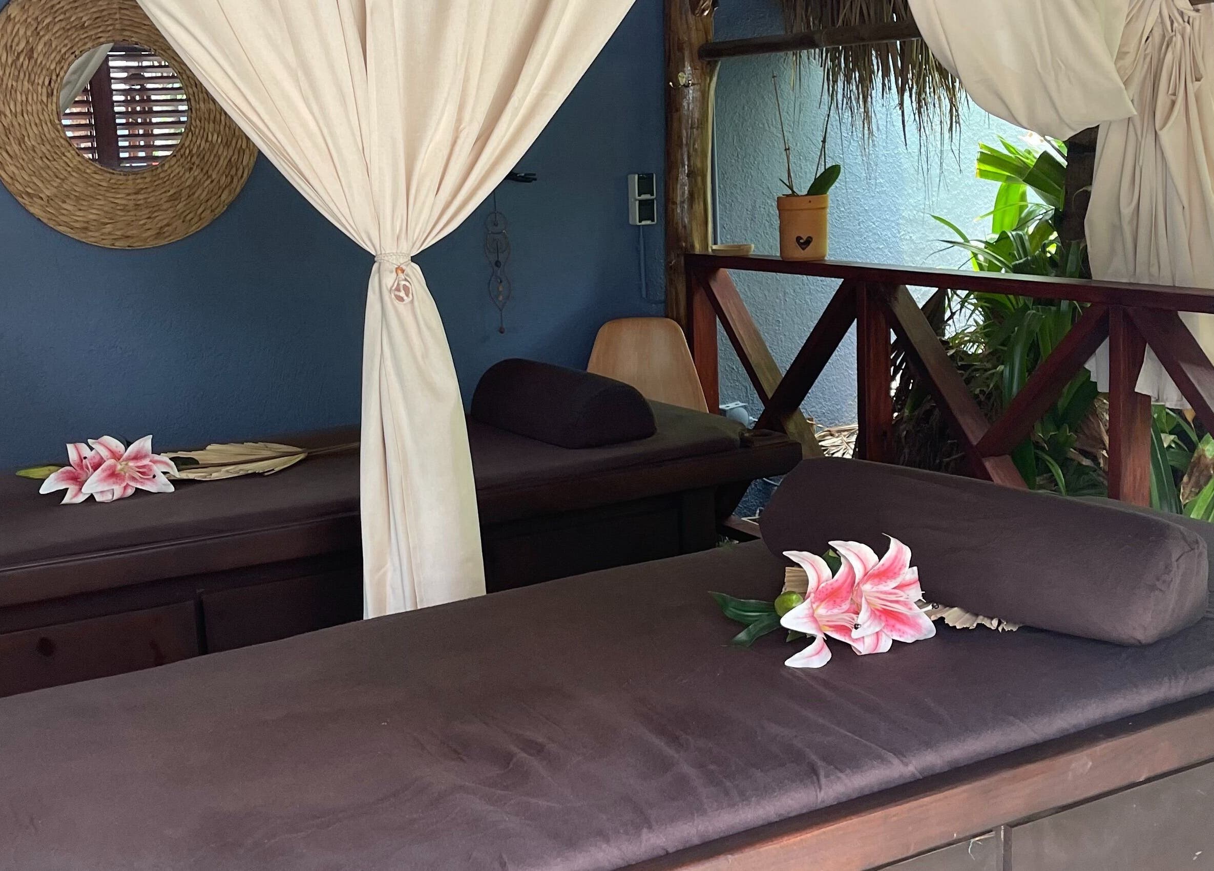 Serene massage setting at I-Relax Massages, Willemstad, CW featuring two beds with lilies and soft drapes.