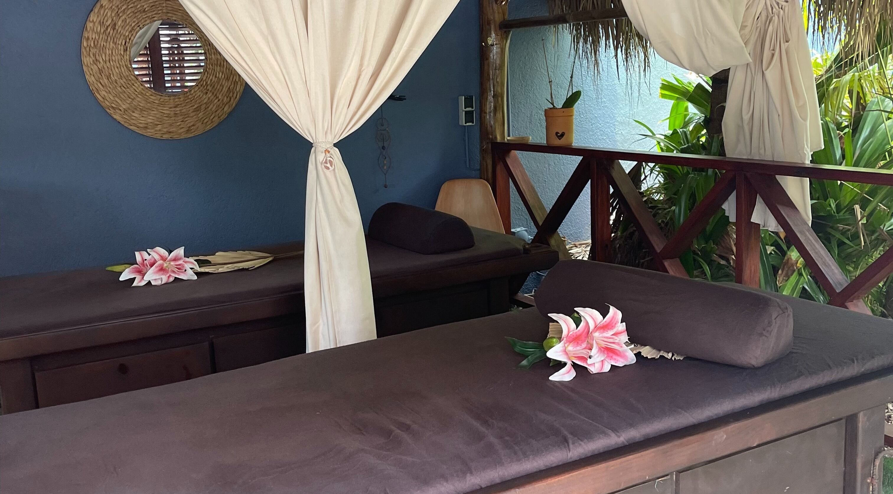 Serene massage setting at I-Relax Massages, Willemstad, CW featuring two beds with lilies and soft drapes.
