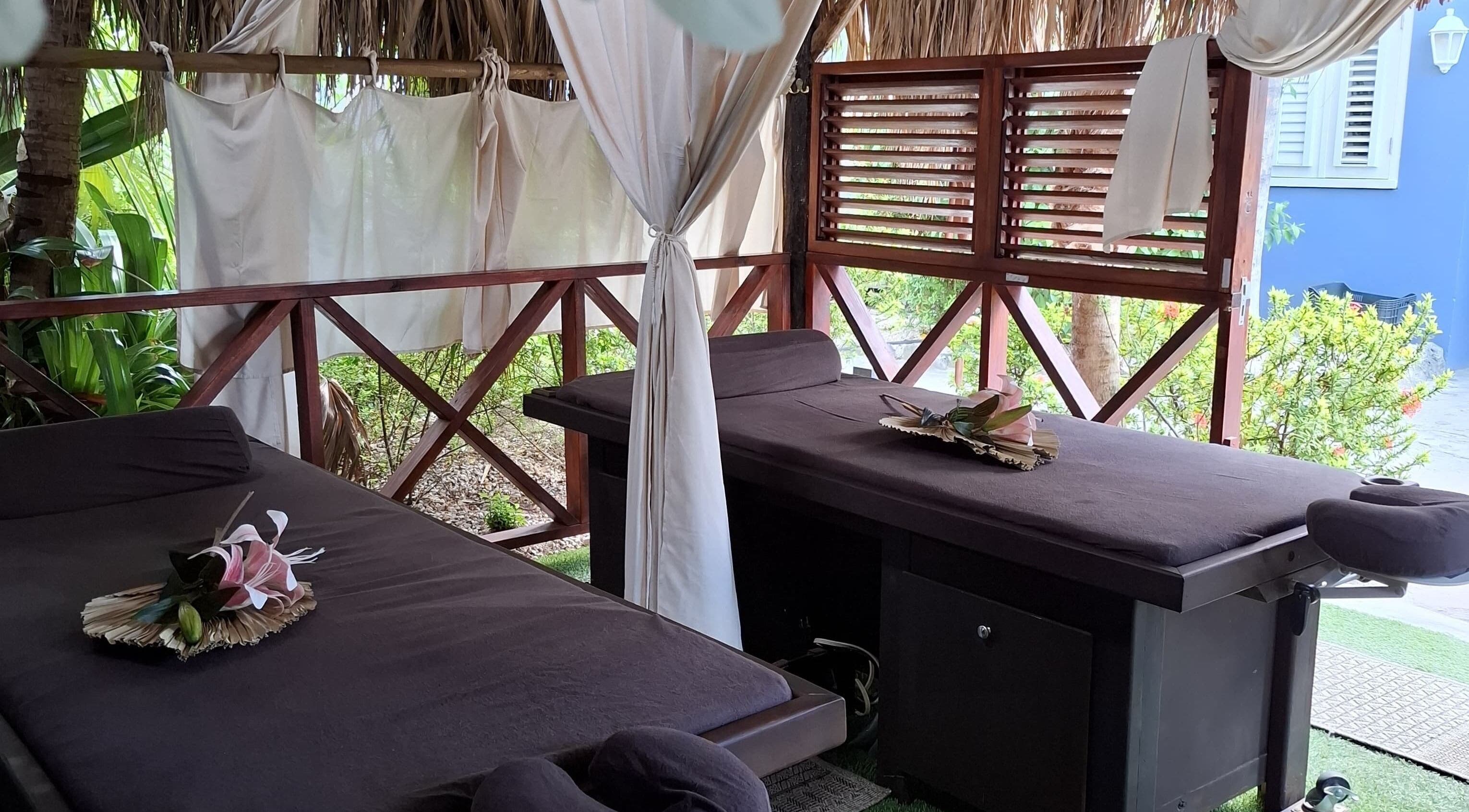 Outdoor massage beds at I-Relax Massages in Willemstad, CW offering a tranquil tropical retreat.