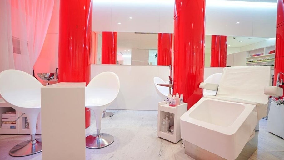 Sleek interior of Nailstation in Dubai, AE with modern chairs and vibrant red accents.