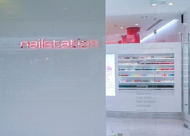 Elegant entrance of Nailstation in Dubai, AE showcasing modern design and colorful nail polish display.