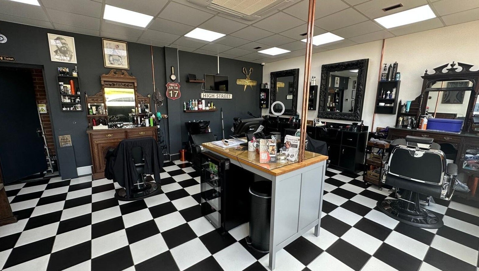 Interior of Can Cuts in Orpington, England, GB showcasing vintage barber chairs and checkerboard flooring.