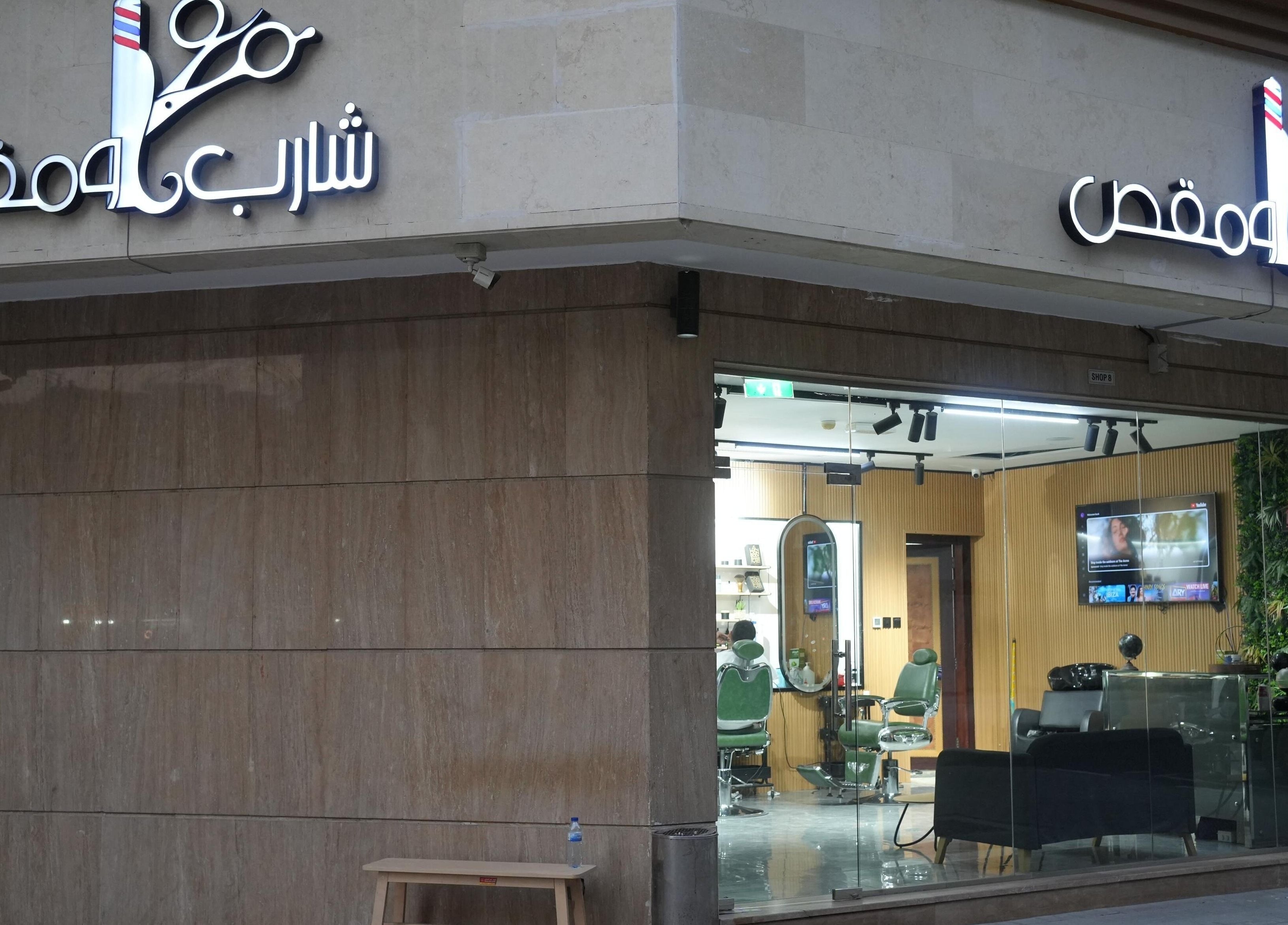 Exterior of Sharb and Maqas Barbershop - صالون شارب و مقص للرجال, Sharjah, Sharjah, AE with glass facade.