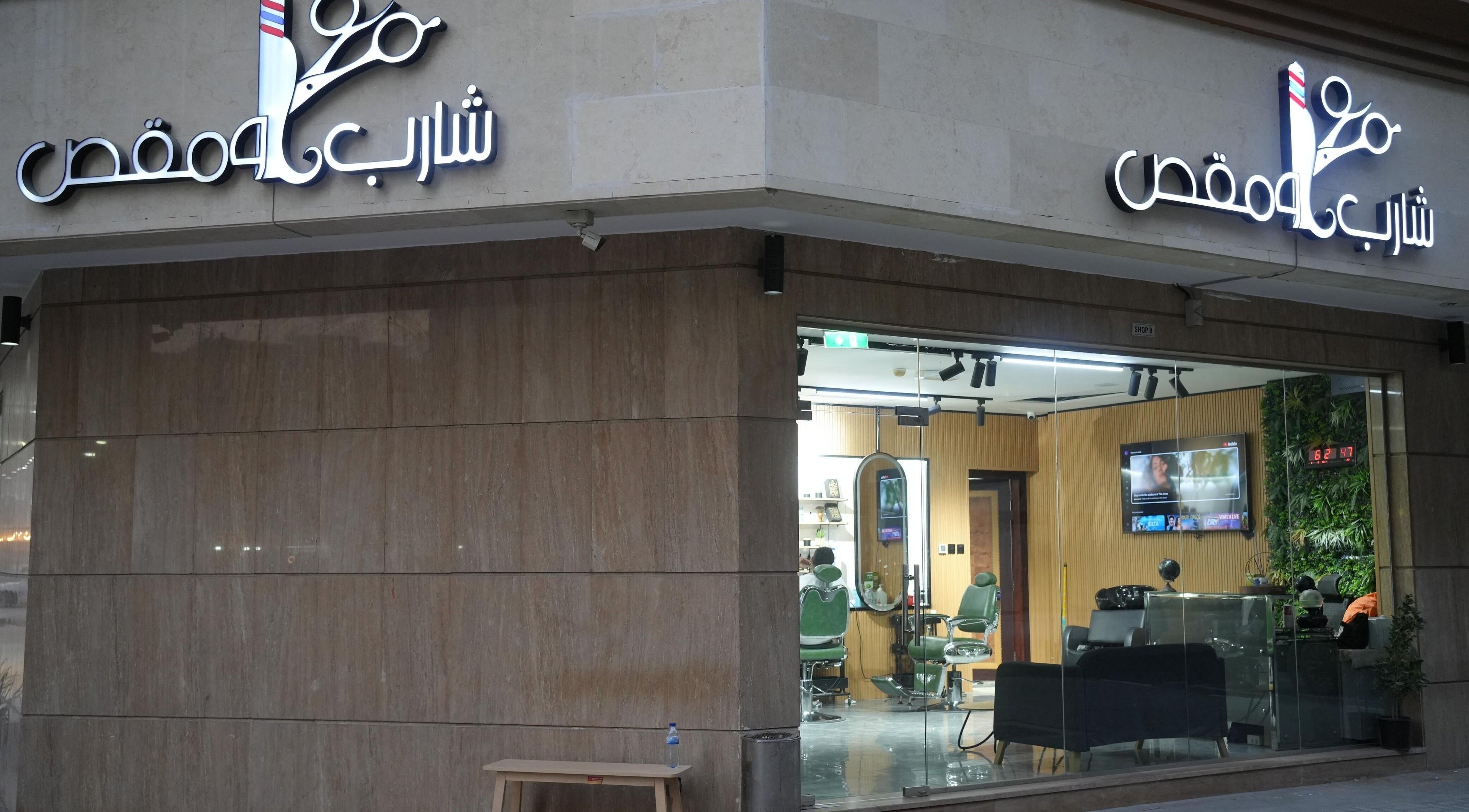 Exterior of Sharb and Maqas Barbershop - صالون شارب و مقص للرجال, Sharjah, Sharjah, AE with glass facade.