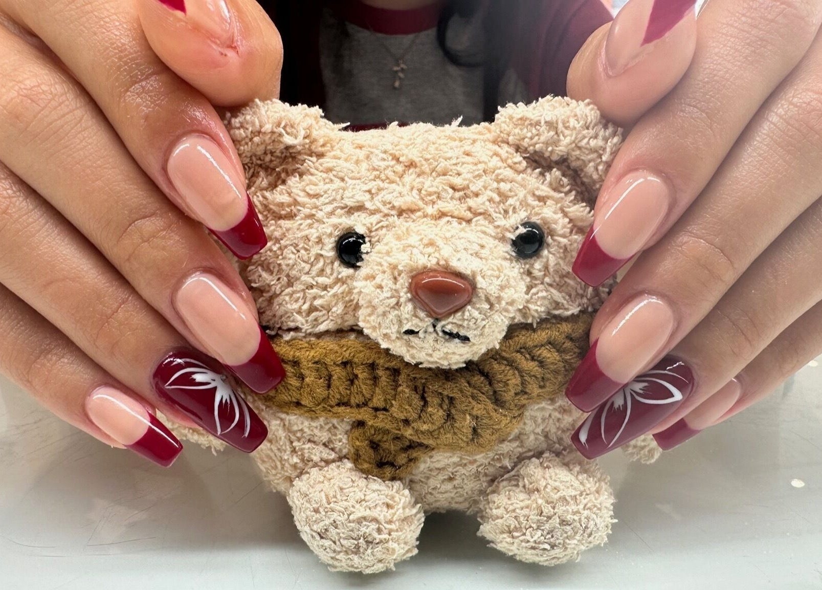 Stylish red French manicure at Laska By Mira, Colindale, England, GB, featuring delicate nail art and plush bear.