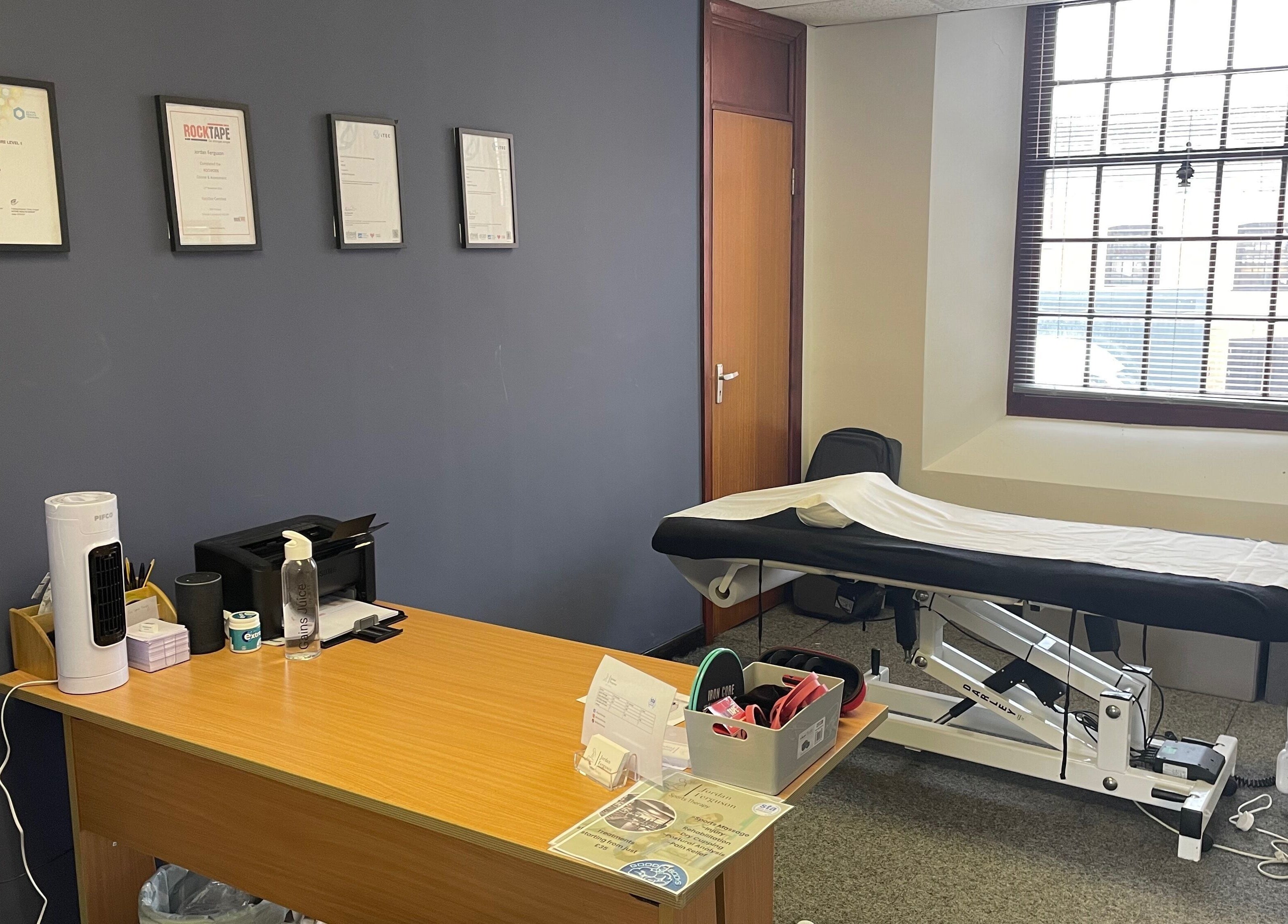 Therapy room at Emerj Fit, Retford, England with treatment bed and certificates on the wall.