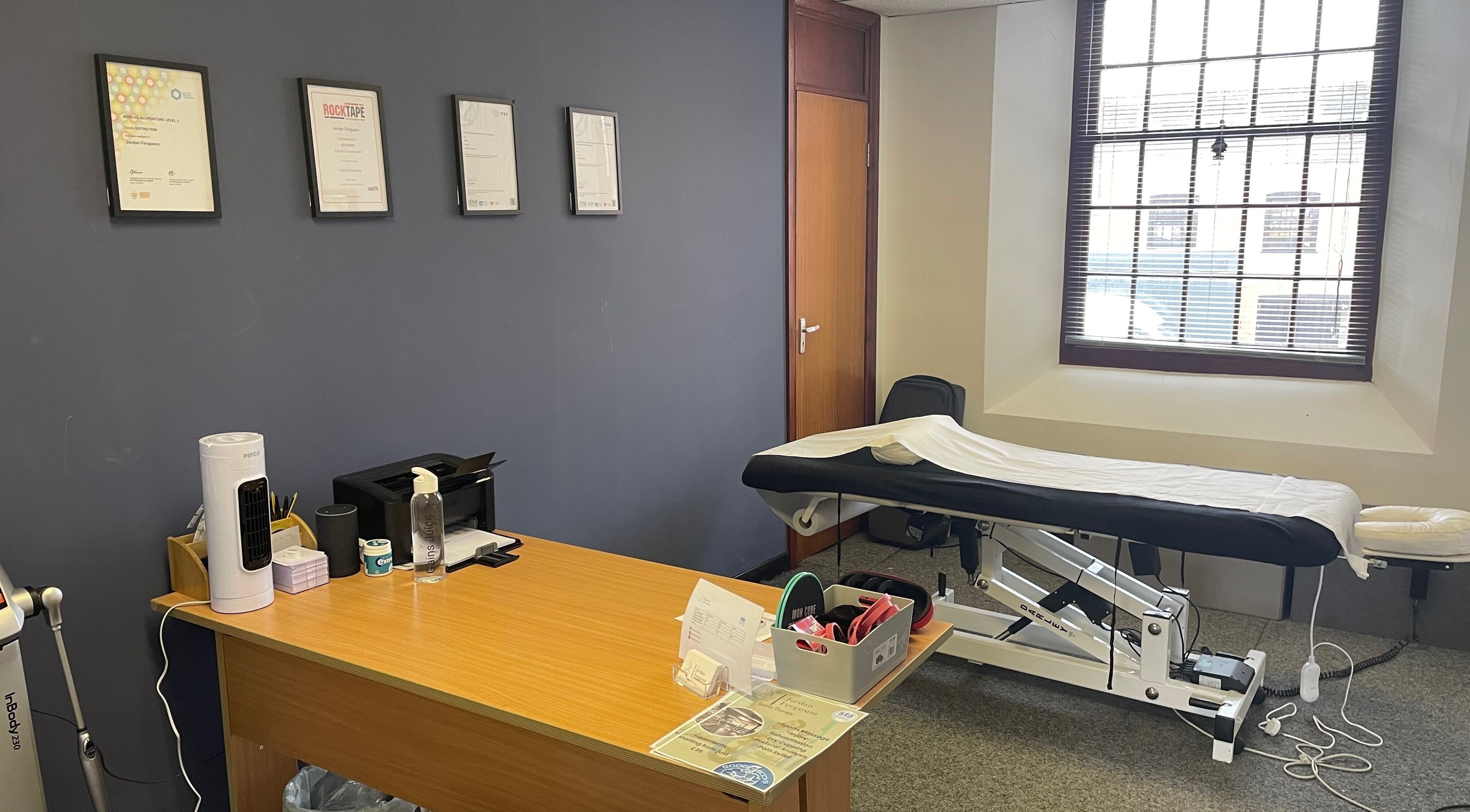 Therapy room at Emerj Fit, Retford, England with treatment bed and certificates on the wall.