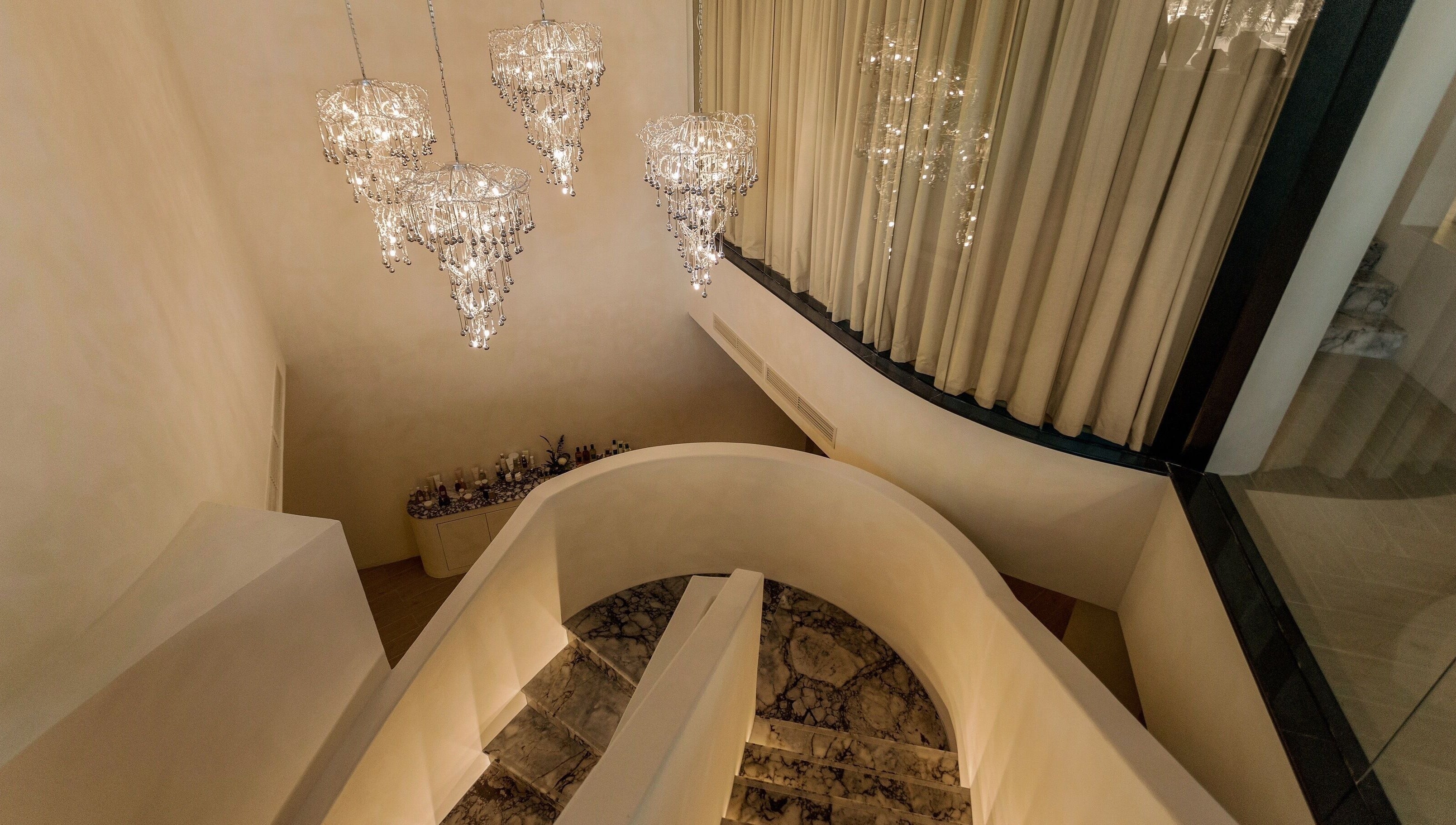 Chandeliers illuminate the grand spiral staircase at Aire MD by Casa Aire Wellness, Dubai, Dubai, AE.
