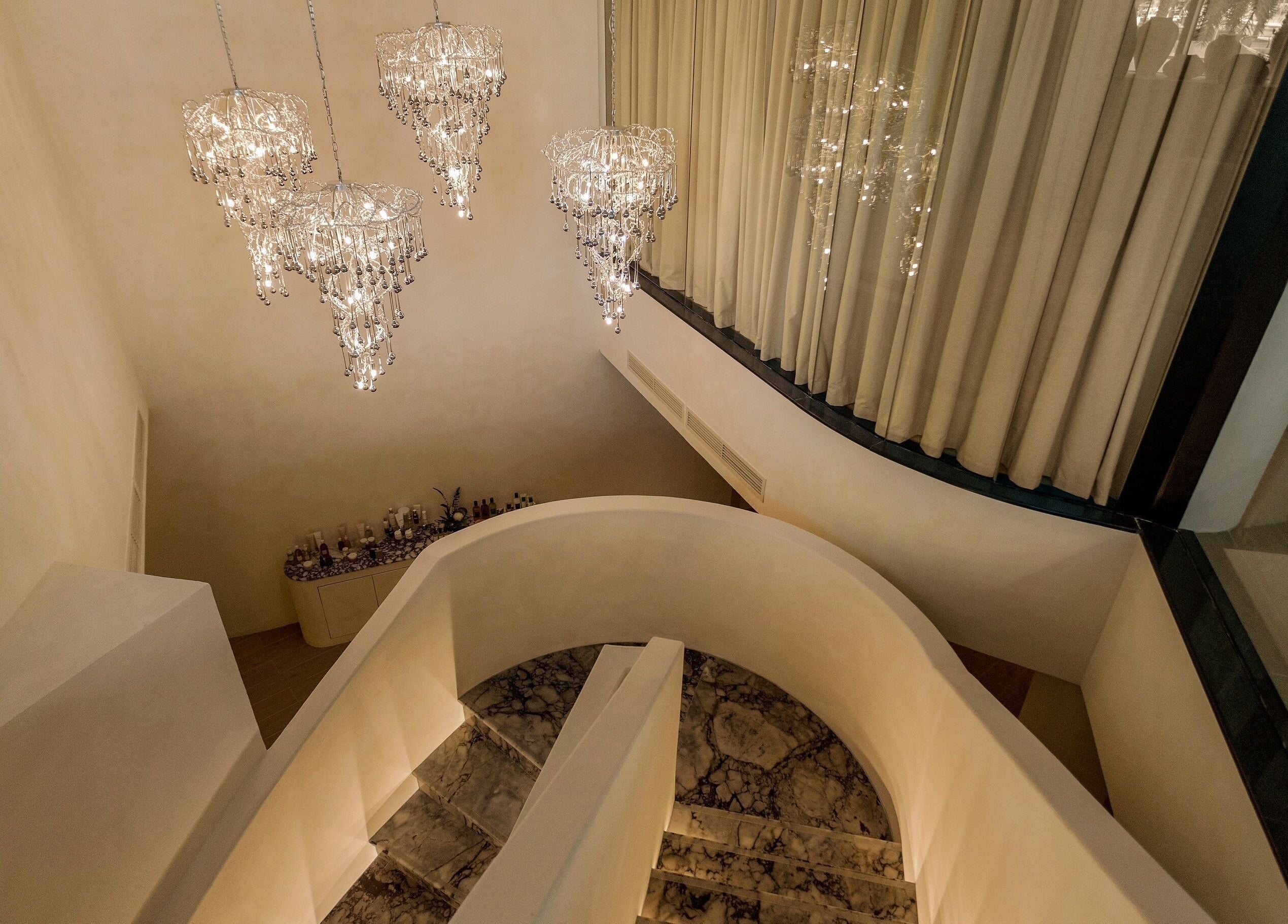 Chandeliers illuminate the grand spiral staircase at Aire MD by Casa Aire Wellness, Dubai, Dubai, AE.