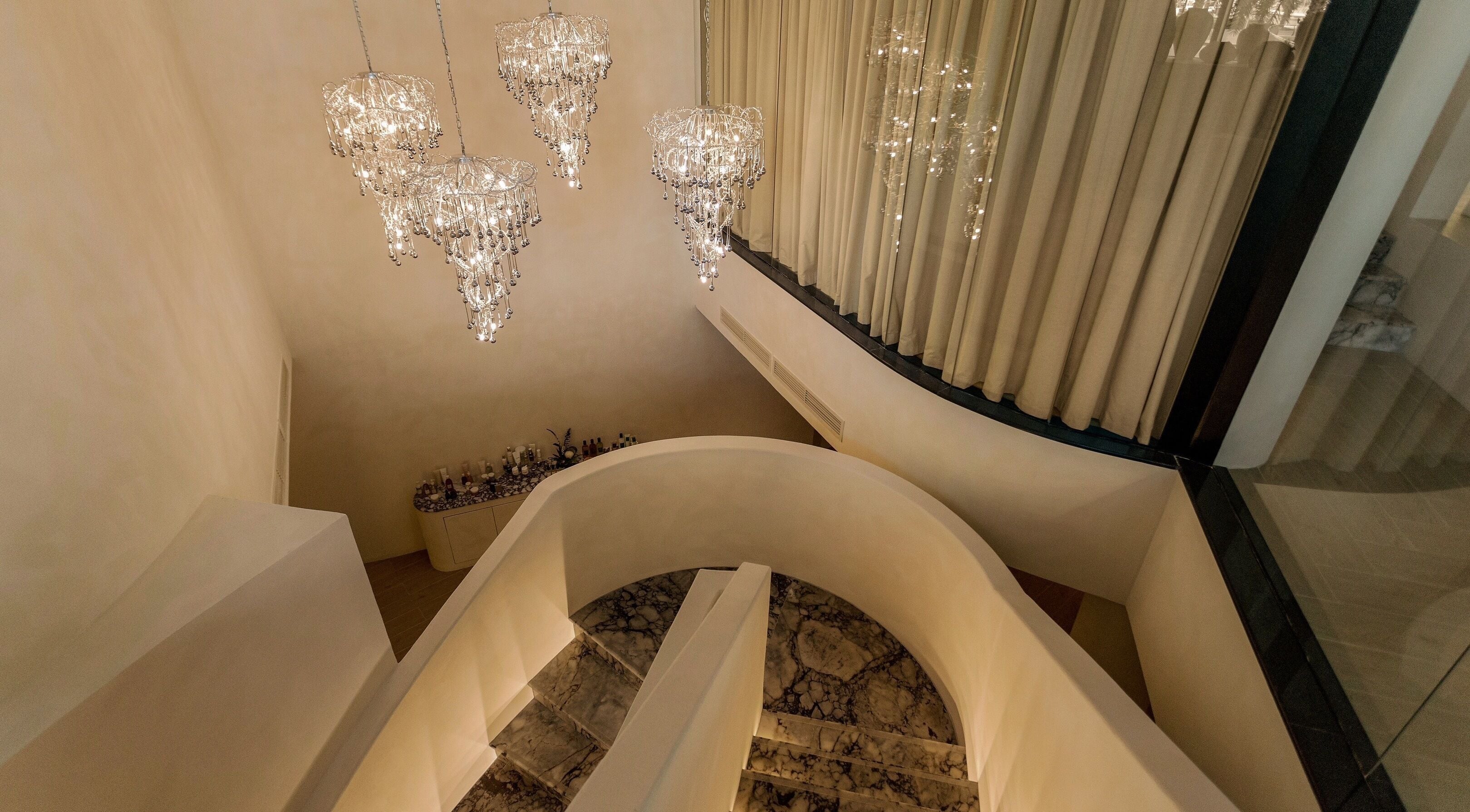 Chandeliers illuminate the grand spiral staircase at Aire MD by Casa Aire Wellness, Dubai, Dubai, AE.