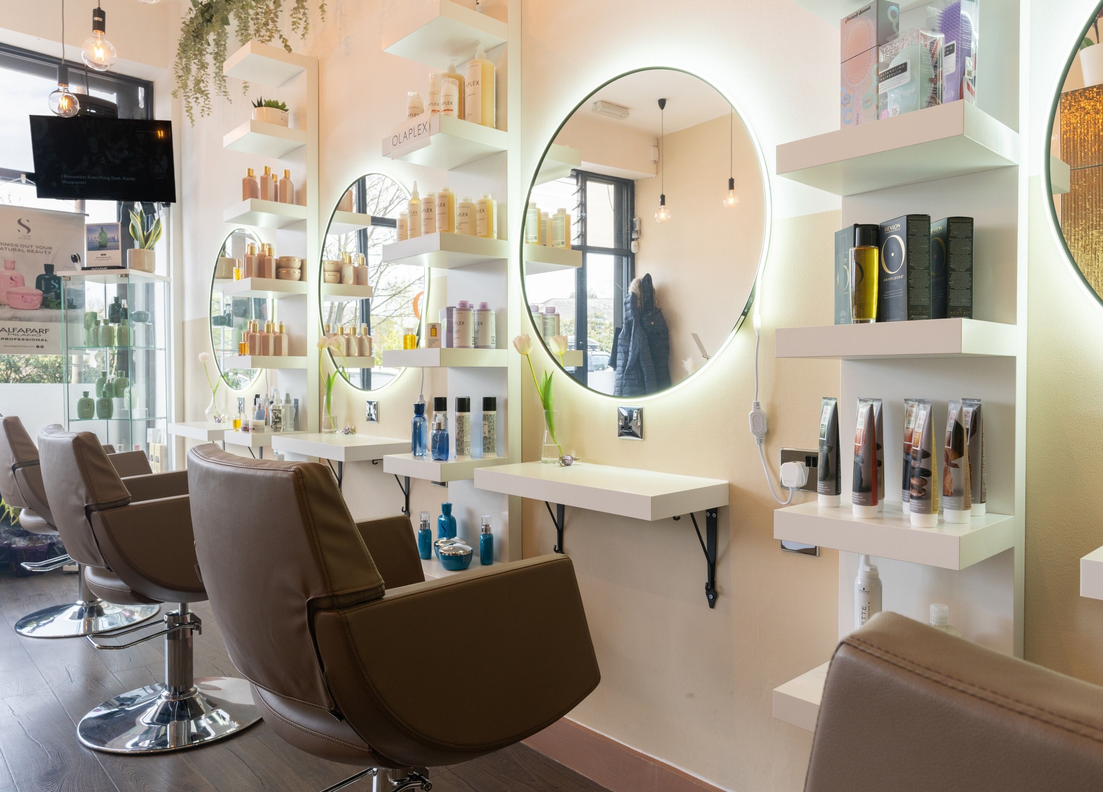 Modern salon interior at Claudia Hairstylist in London, England, GB featuring chic chairs and illuminated mirrors.