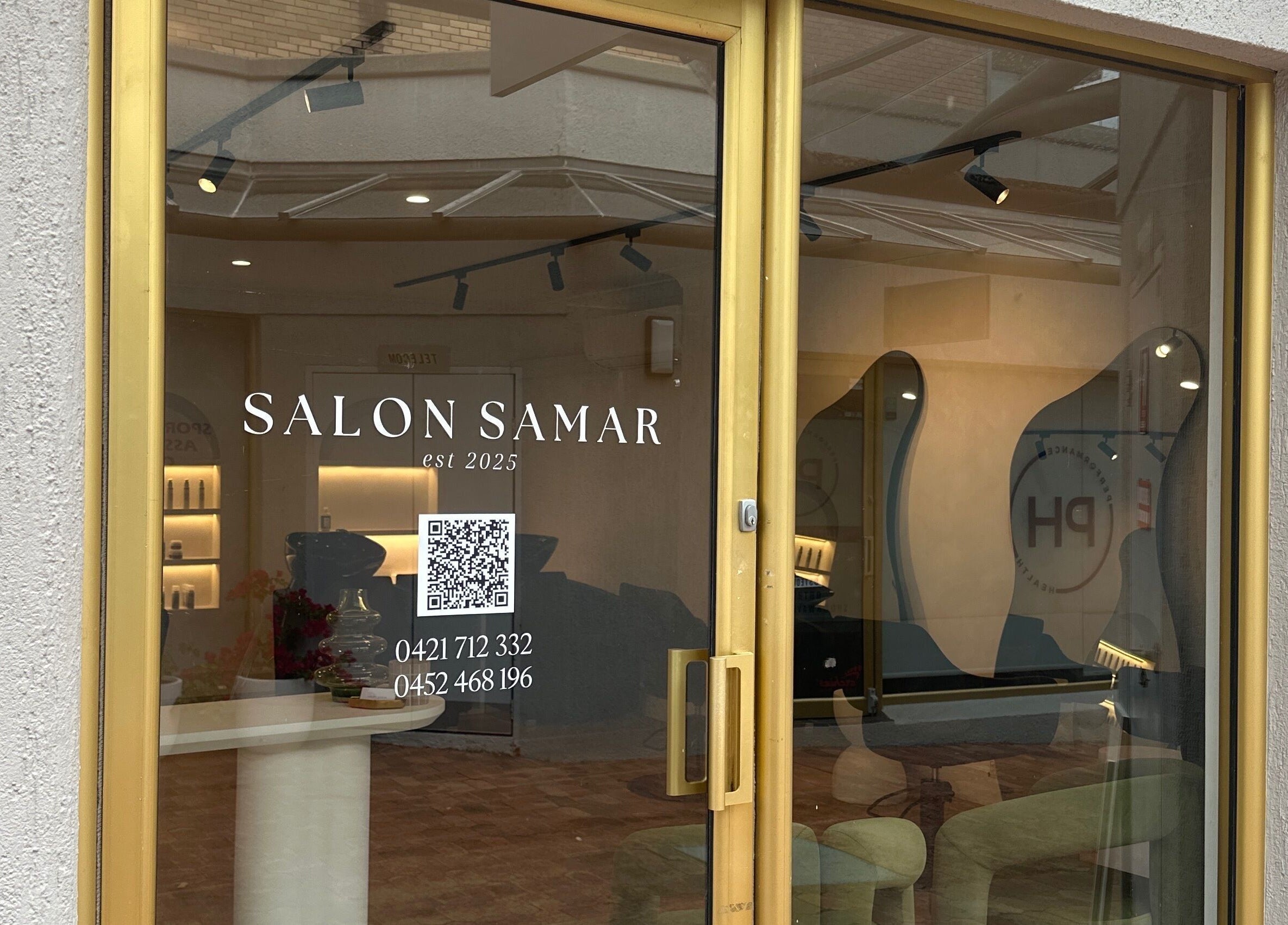 Entrance of Salon Samar in Newport, New South Wales, AU, featuring modern interior and gold-framed glass door.