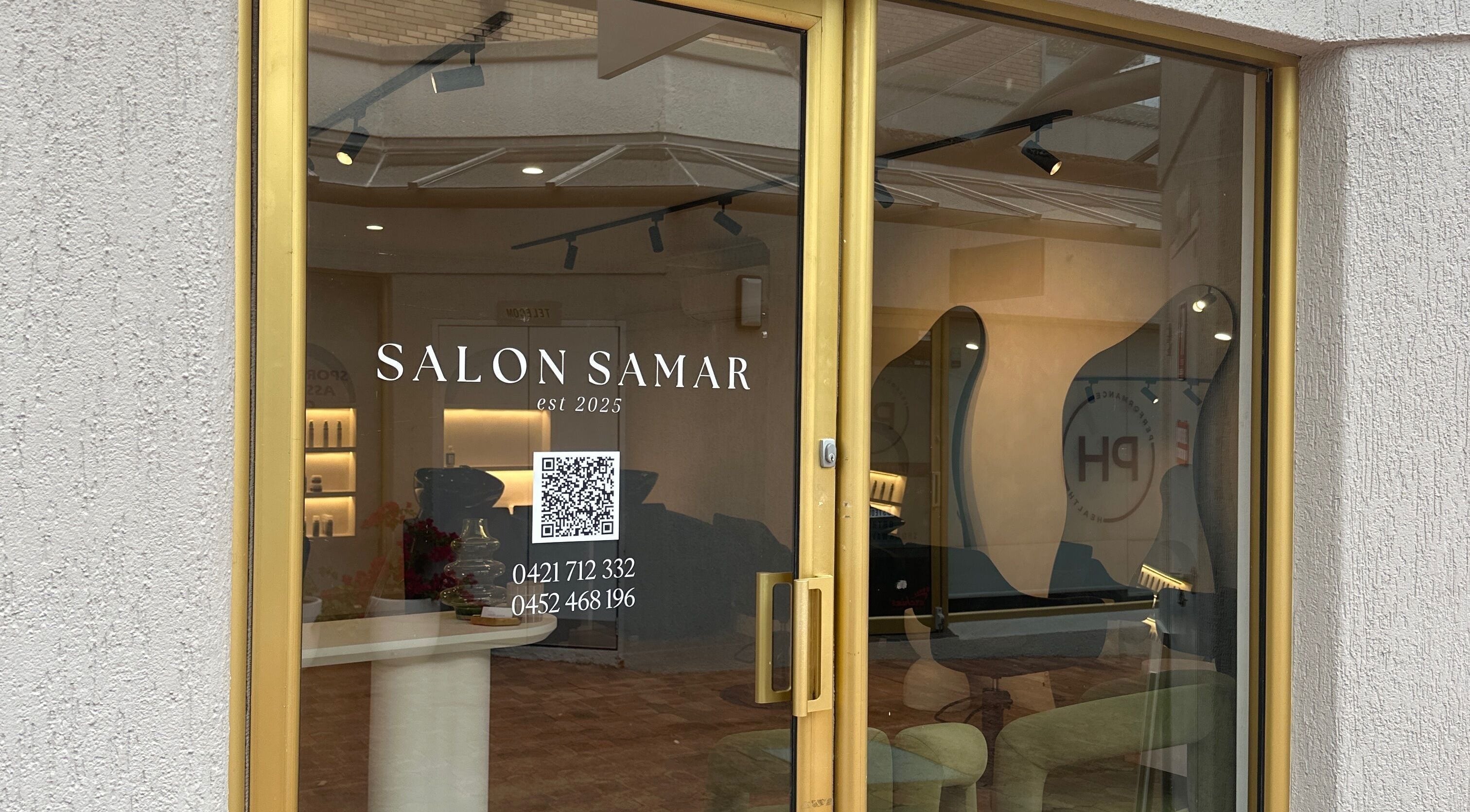 Entrance of Salon Samar in Newport, New South Wales, AU, featuring modern interior and gold-framed glass door.
