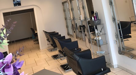 Elegant interior of Styled by Court salon in Sutton, England, GB with sleek styling chairs and framed mirrors.
