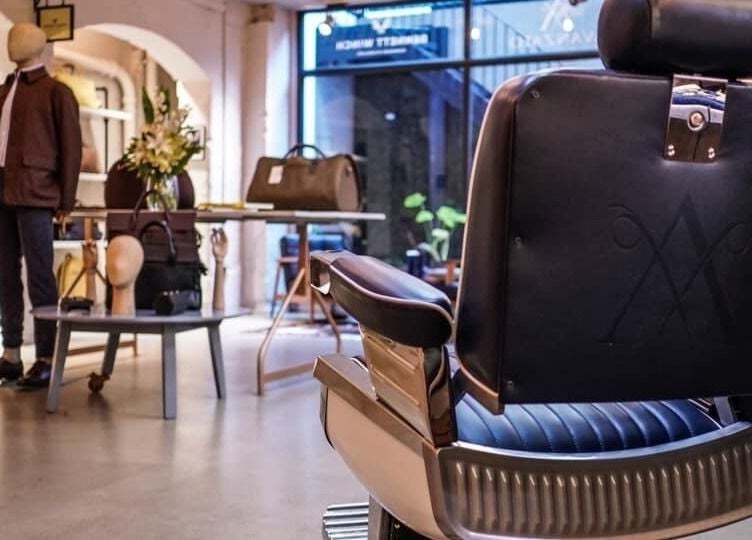 Modern barber chair at Avanzato Grooming Lounge, London, England, GB with stylish decor in background.