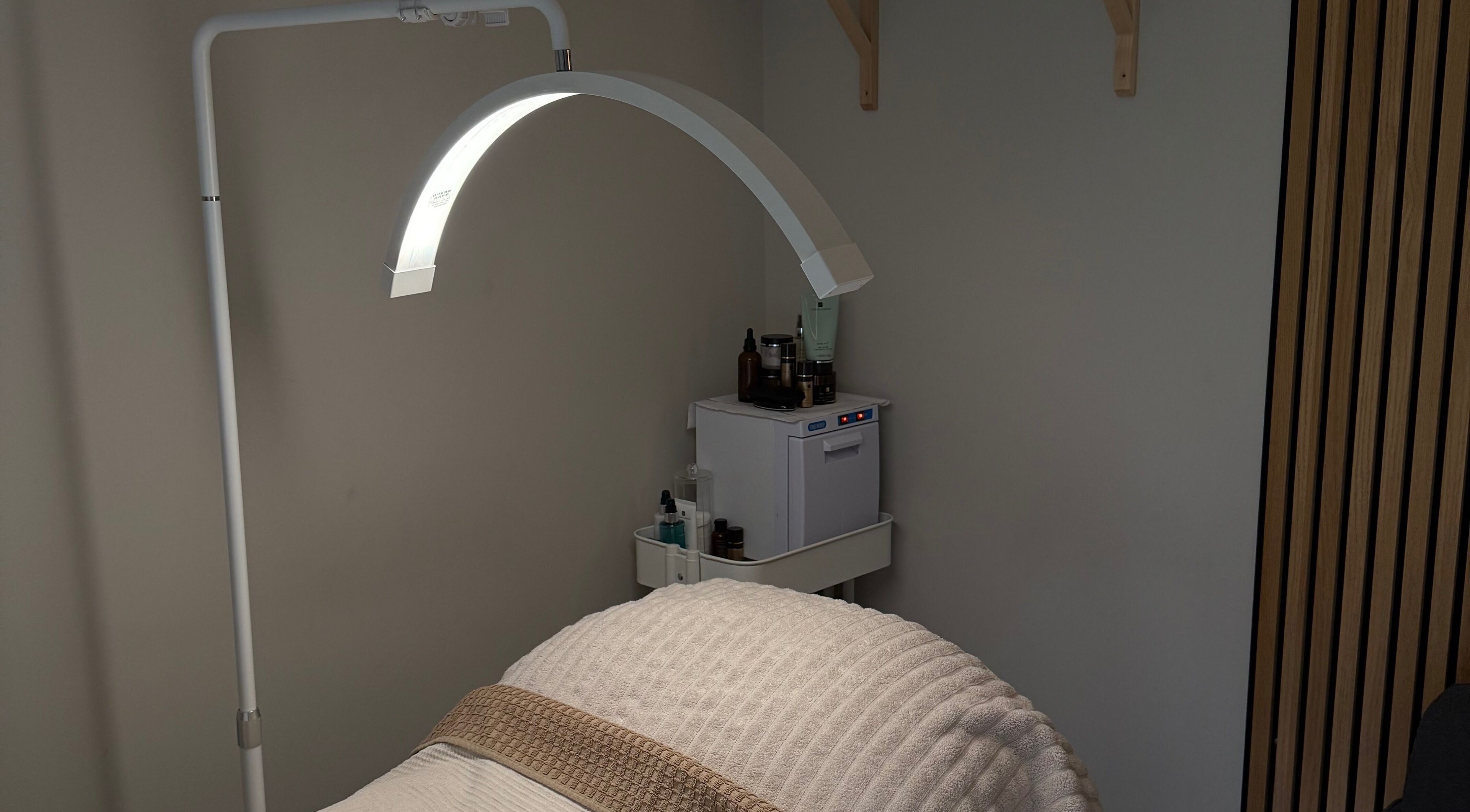 Cozy treatment room at Lucy Watson Beauty, Horsham, England, GB with bed and lamp.