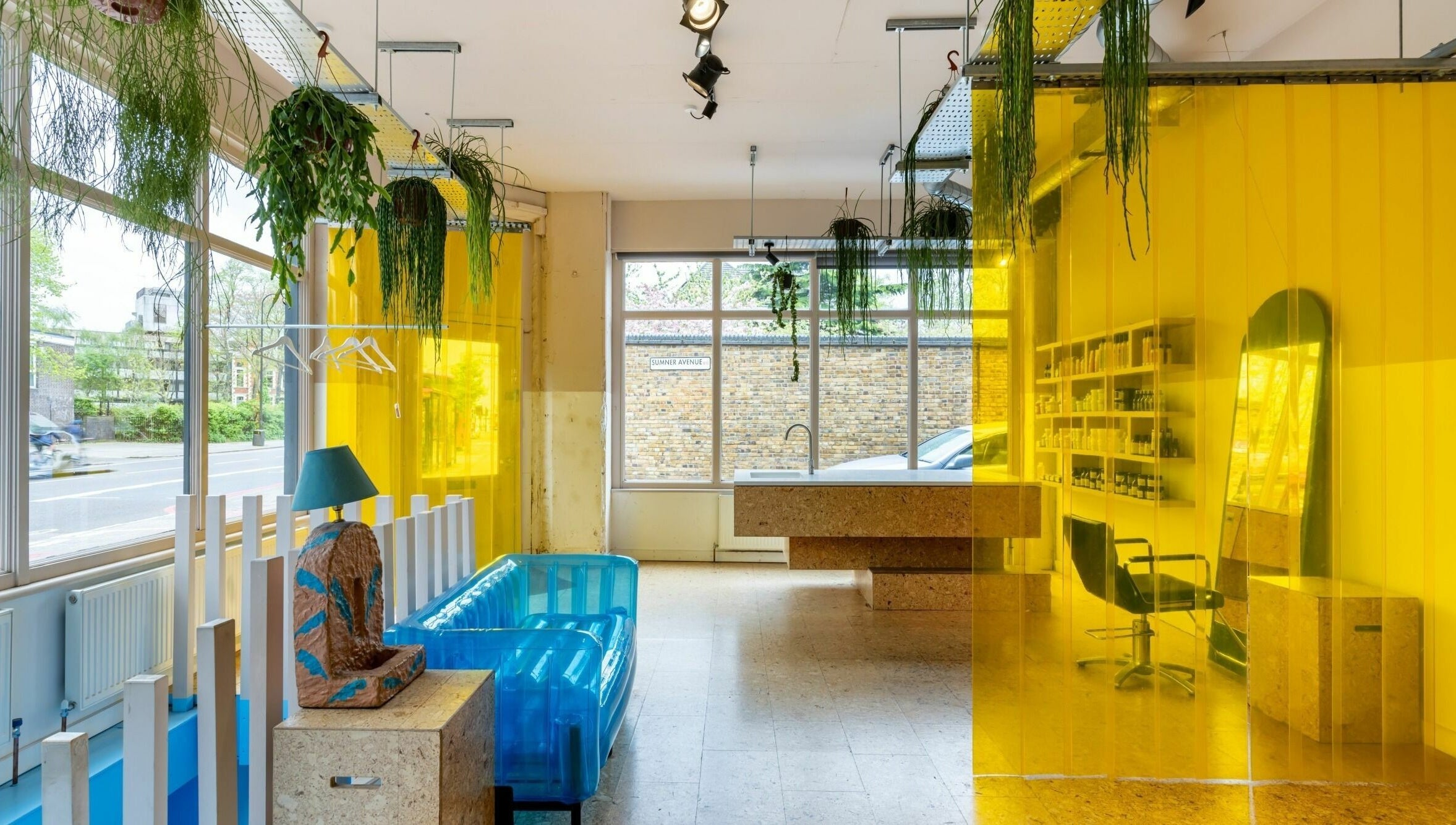 Bright interior of Crab Salad Peckham in London, GB with yellow dividers and greenery accentuating blue seating.